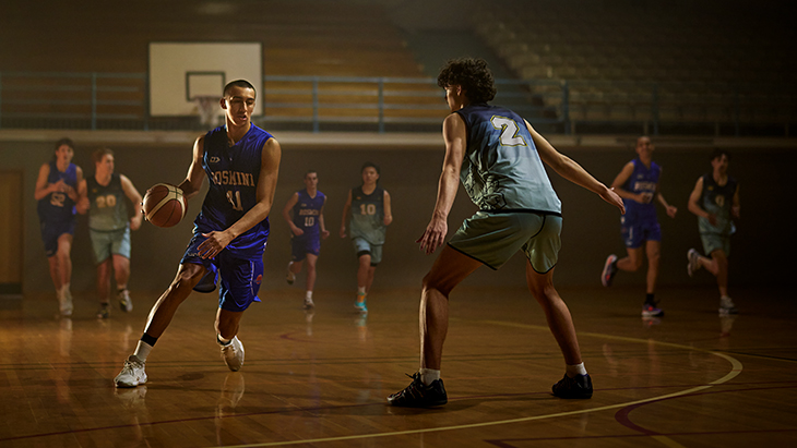A male basketball player dribbling the ball. 