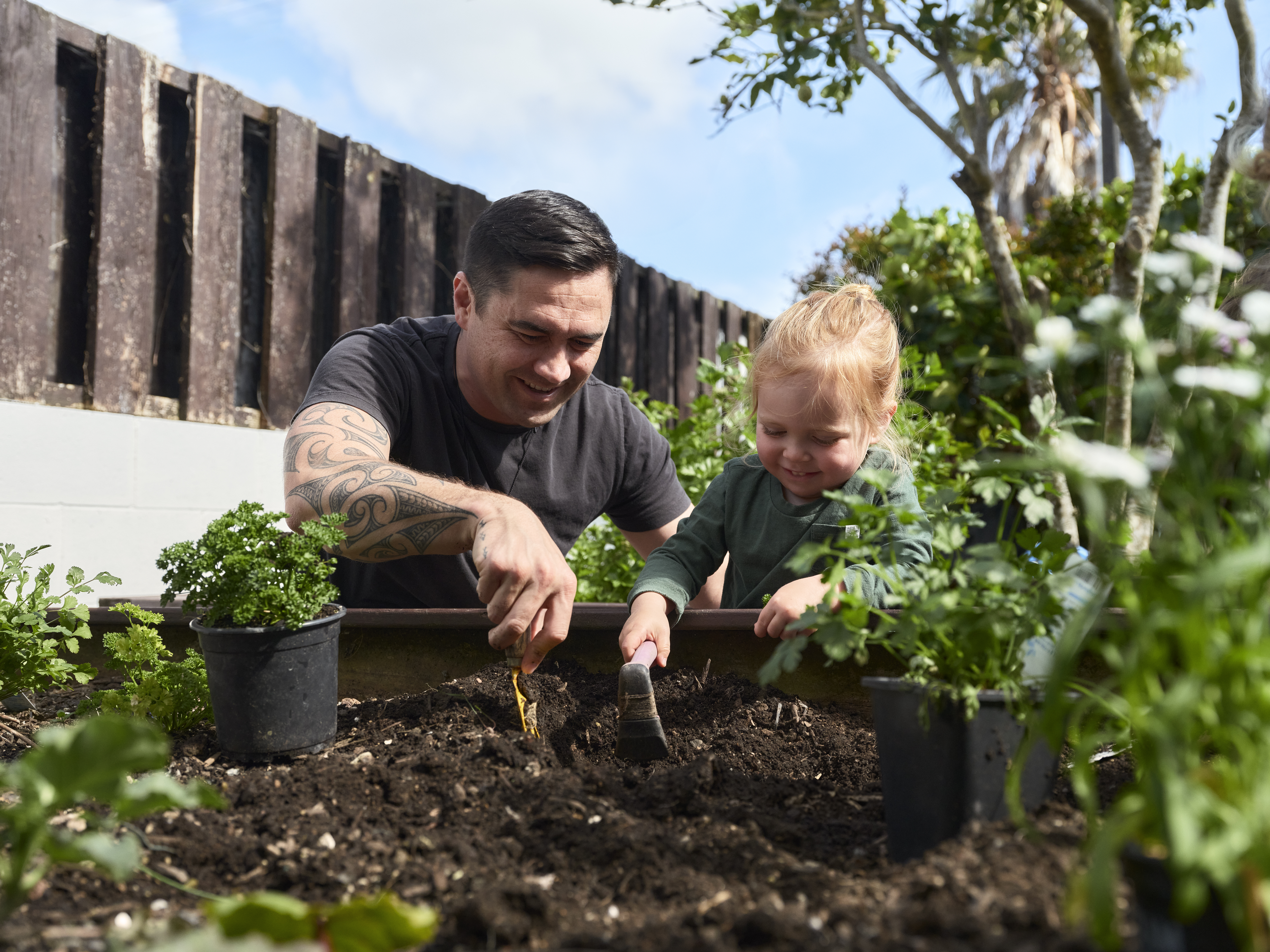 Man and young girl work on the garden