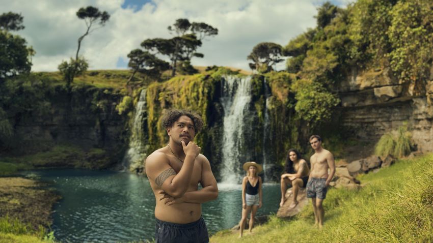 Man having a hmmm in front of waterfall with friends in background looking on