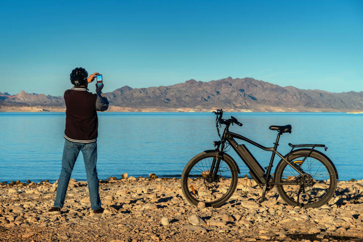 Older man takes photo of landscape with his e-bike in the foreground
