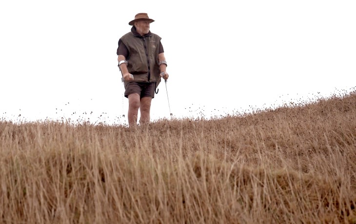 Chris Biddles stands atop of a hill with crutches