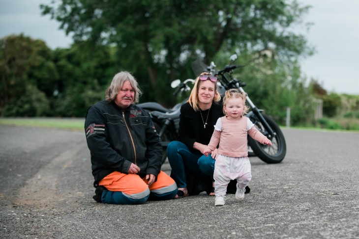 Kavana, young Harley and her Dad pose in front of a motorbike