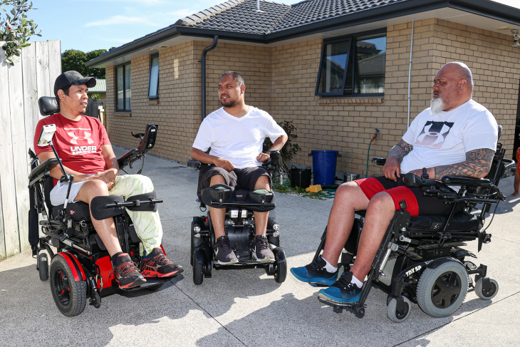 Lee sits with his friends in the driveway, all in their wheelchairs