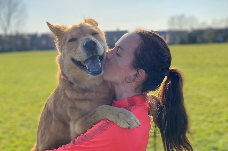 Liv Chance cuddles her dog on the field