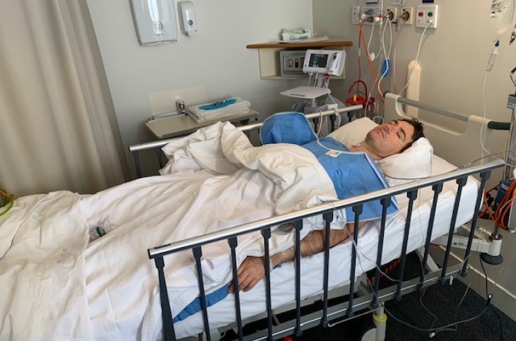 Luke Henley lies on his hospital bed