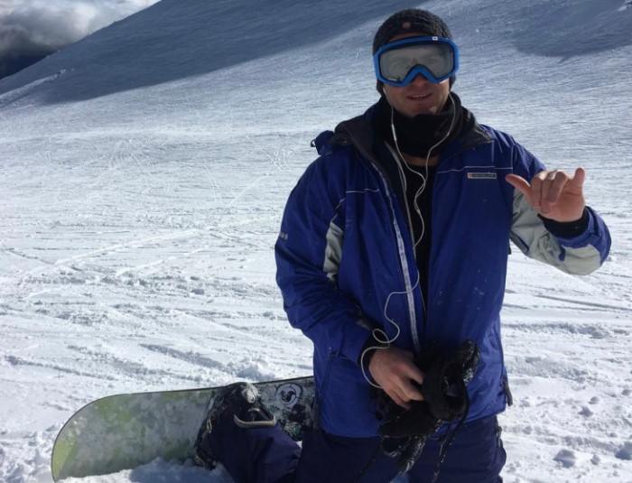 Luke Henley gives a hand sign to the camera while snowboarding