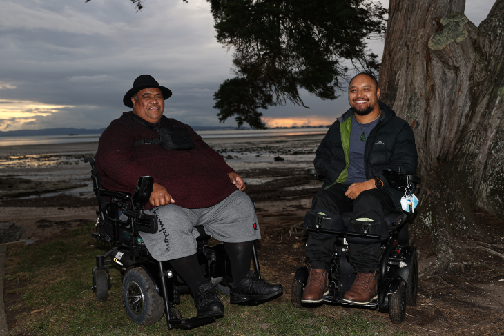 Lee and his friend park their wheelchairs by the beach at dusk