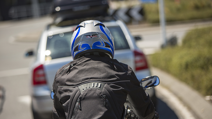 Motorcyclists sitting behind a car at a roundabout