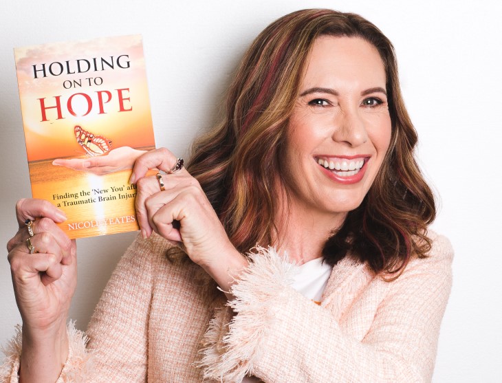 Nicole Yeates holds up her book 'Holding on to Hope' for the camera