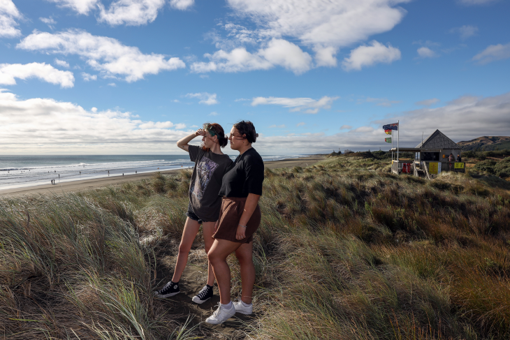 Paris and her sister look out from the surf livesaving shed to Muriwai beach