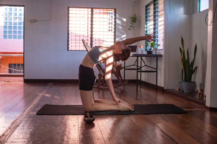 Young woman stretches on her knees