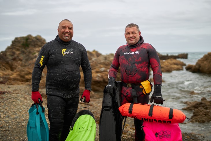 Todd and Rob pose in their dive gear by the sea
