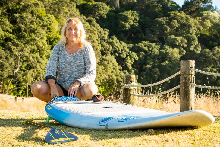 Verity Thom sits by her paddleboard on the beach