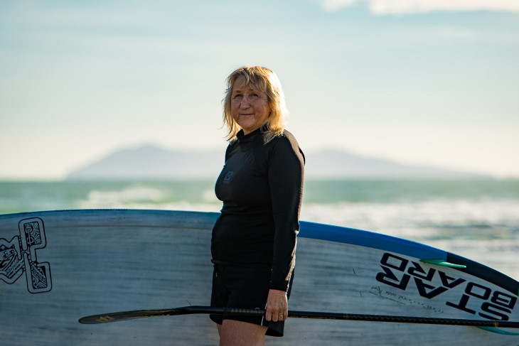 Verity Thom holds her paddleboard by the sea