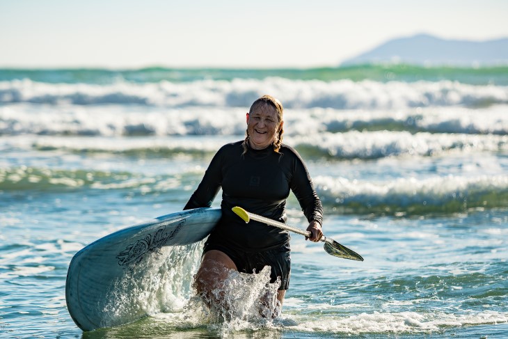 Verity Thom walks back from a surf with her board