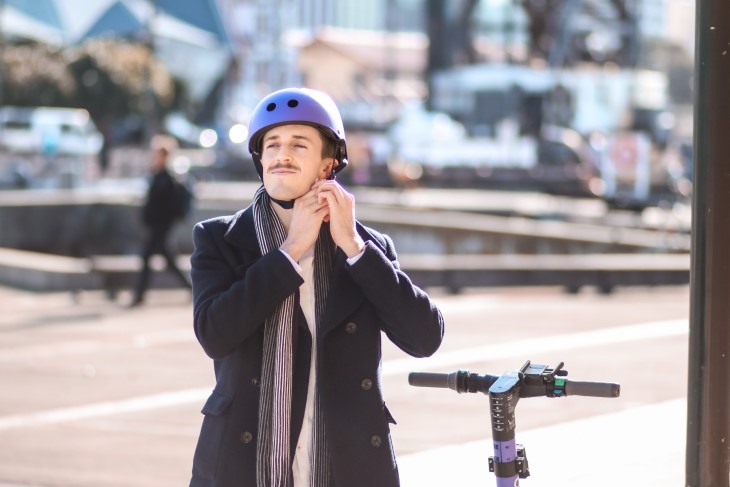 Guy clips up helmet before riding e-scooter