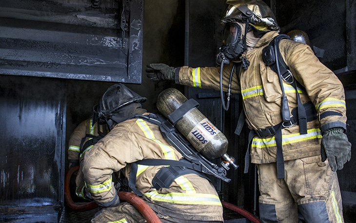 Firefighters running a hose in a training environment
