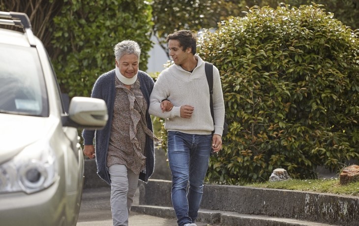 Young man helps older woman walk