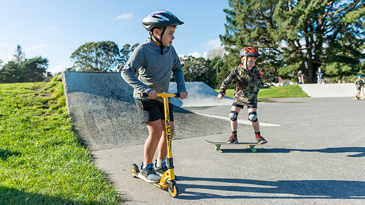 Kids on scooters at a skate park