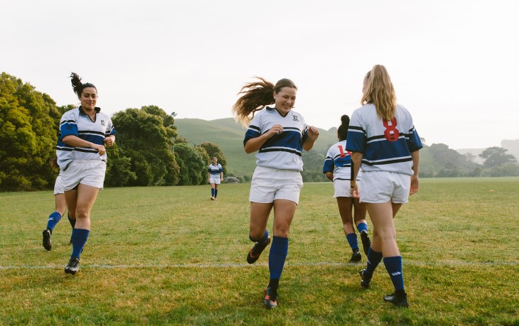 A women's rugby team running sprints as a warm up pre-game.