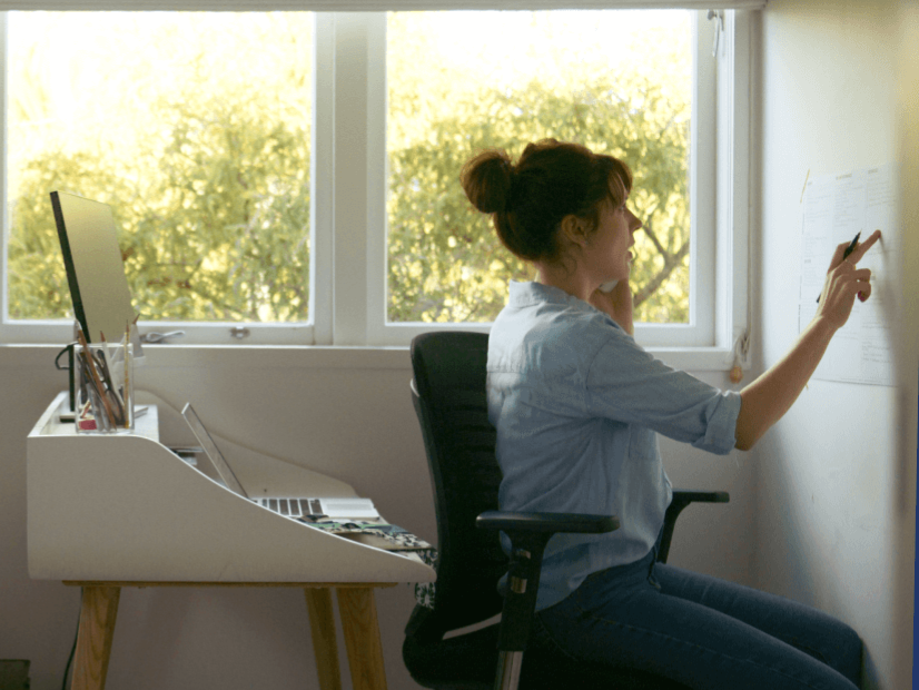 Person sitting at desk and writing on a whiteboard