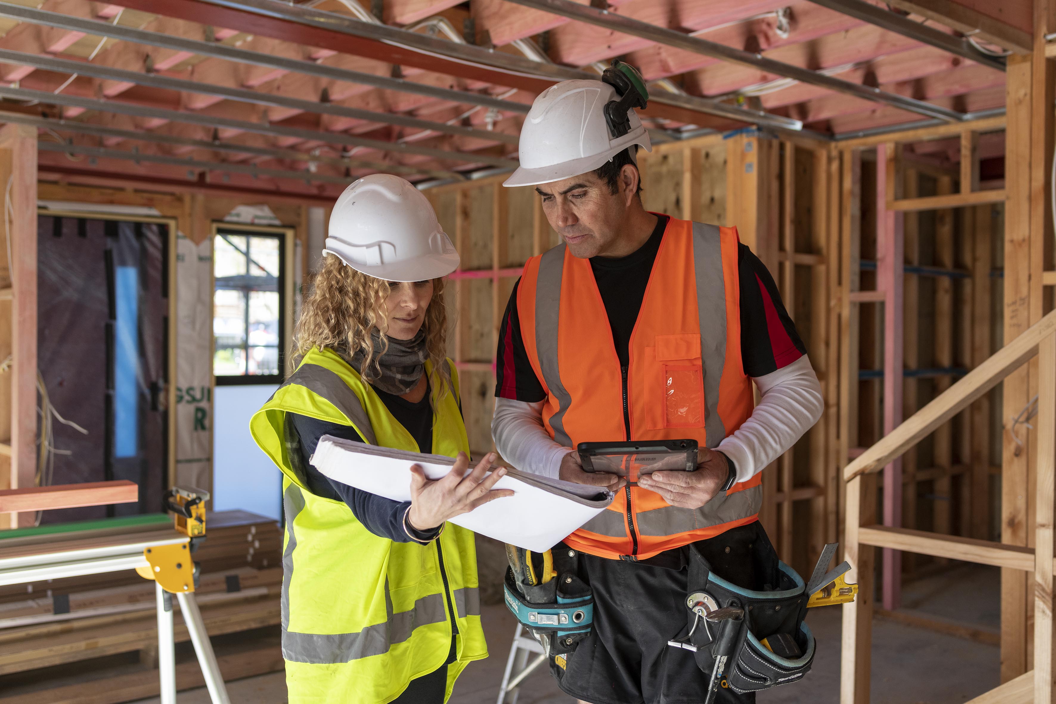 Two workers in hi vis looking at plans on site