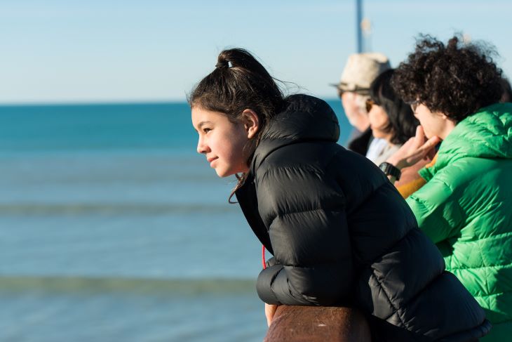 Girl with family on the pier looking in to the distance 