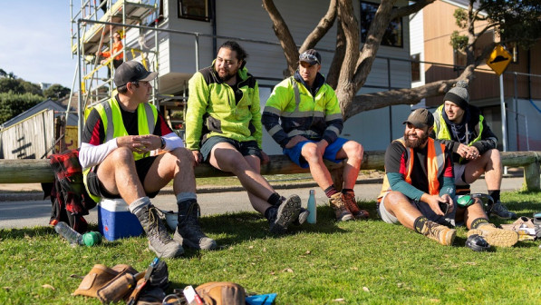 Builders taking break on grass outside building site