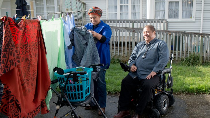 Man in wheelchair and carer hanging washing