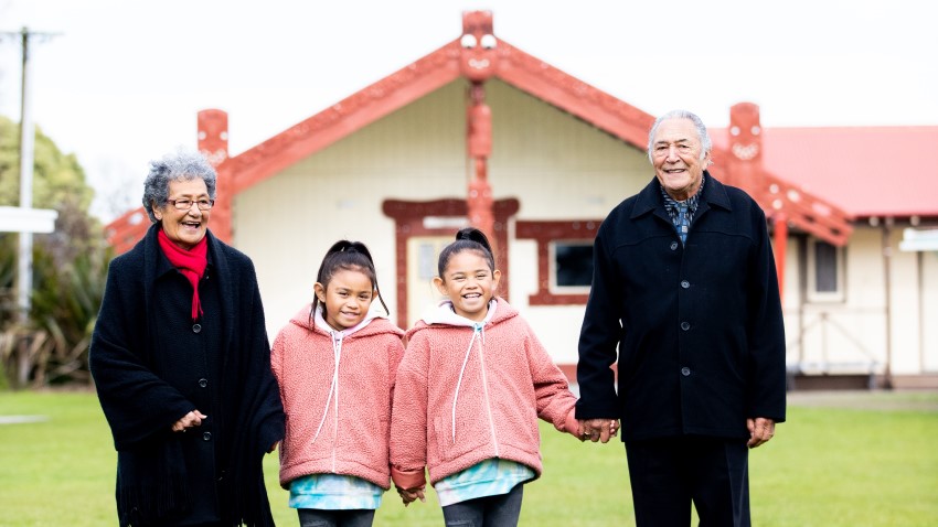 Grandparents and tamariki standing in front of marae