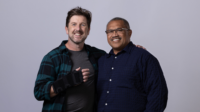 Injured employee with wrist support and arm around employer both smiling at camera