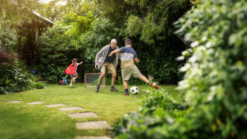 Grandfather playing soccer with grandkids