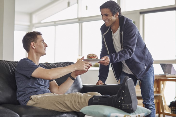 Young man hands injured friend a plate of food