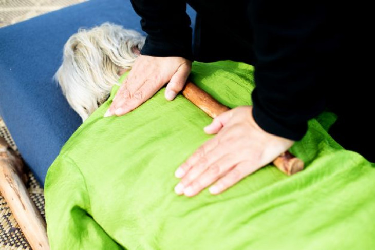 Rongoa Maori practitioner applies healing to someone's back