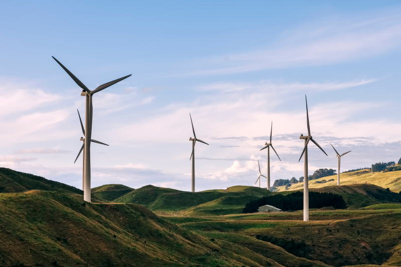 Wind turbines on the top of grassy hills in the country. 