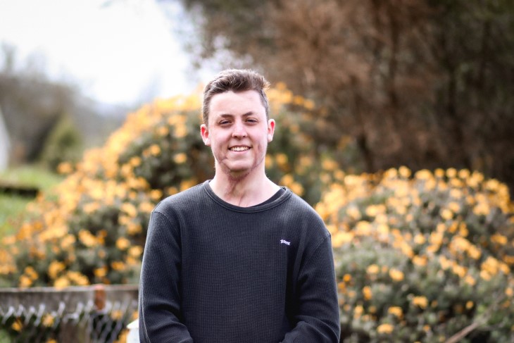 Brayden Warnock-Hannon smiles for the camera in front of some bushes