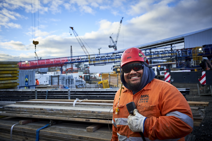 A construction worker smiling at the camera on a building site. 