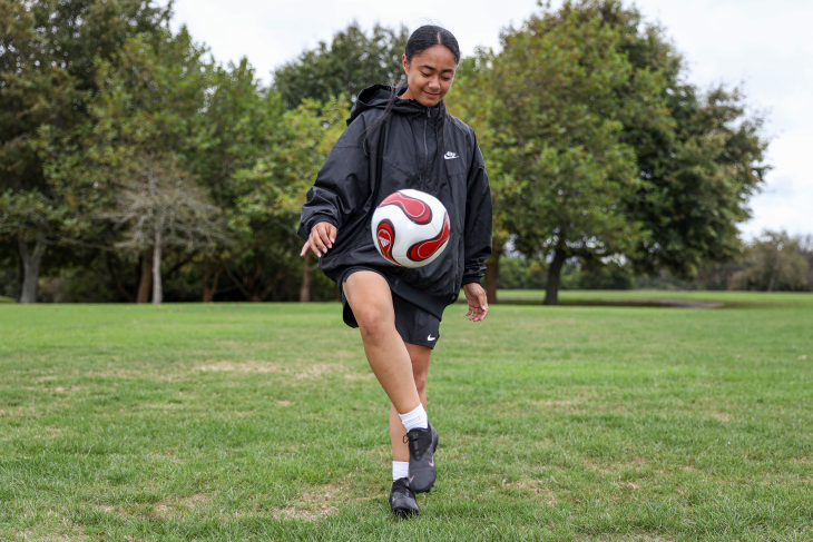 Carla kicks a football in the air