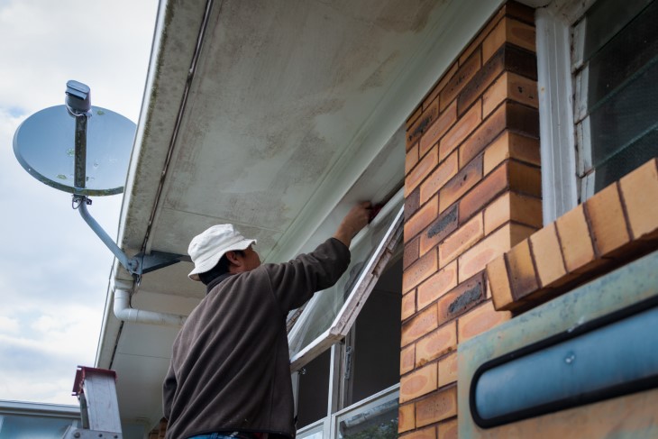 A man painting the frame of a window. 