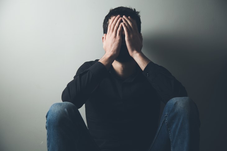 Depressed man sitting with his head in his hands.