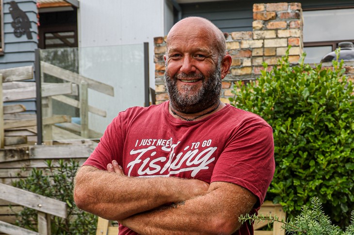 Derek Eady arms crossed smiling at the camera in a red t-shirt