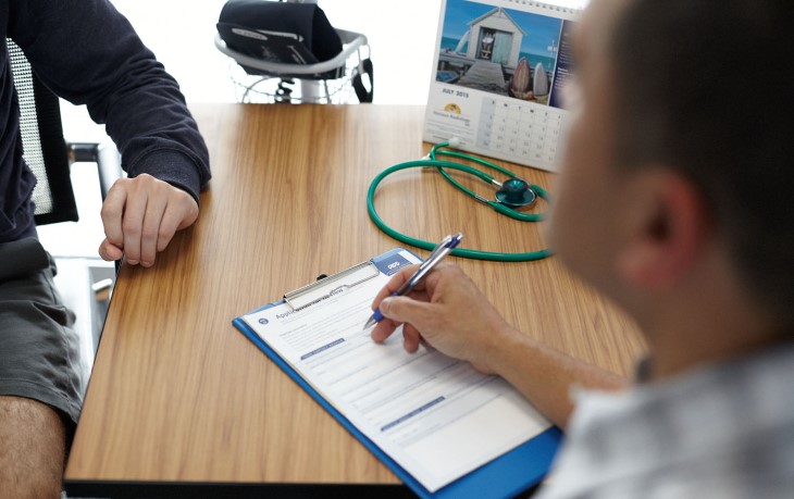 Doctor fills in a form with a patient