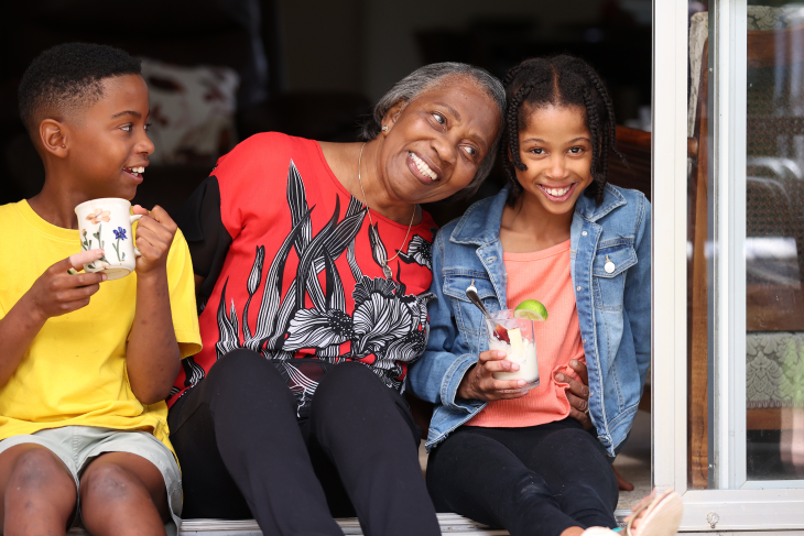 Dorothy Fitzpatrick sitting with her grandchildren and smiling. 