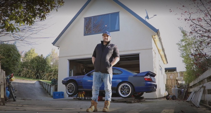 Josh stands in front of his car at his house