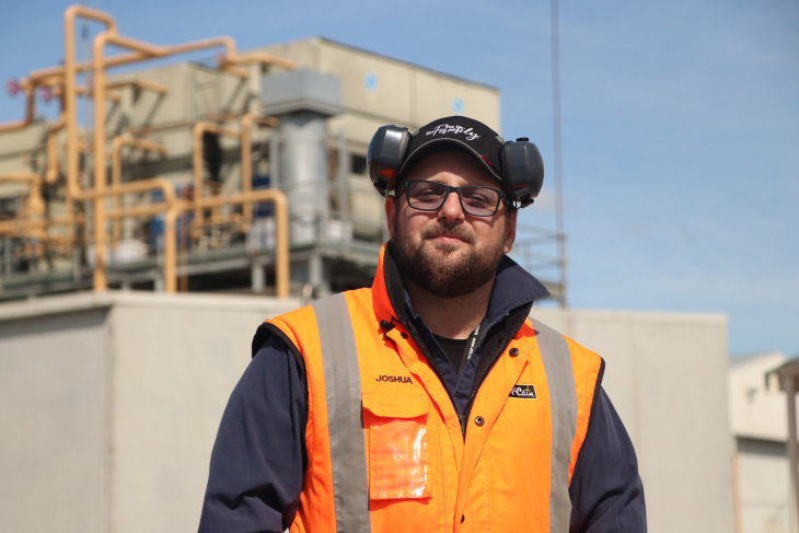 Josh stands in front of the factory