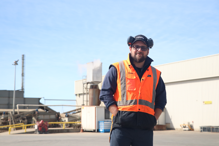 Josh stands in front of the factory