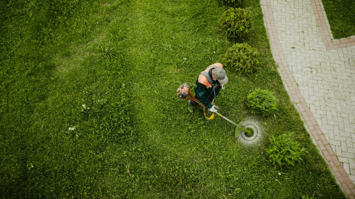 Wide shot of man cutting lawns.