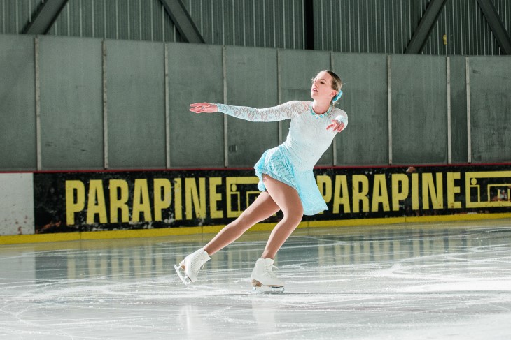 Lydia skates on the ice with her arms out by her sides