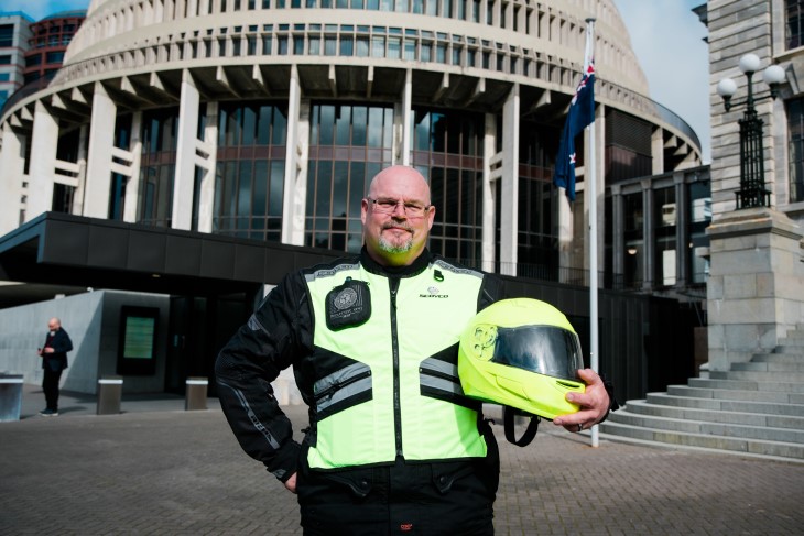 Ross smiles for the camera in front of the Beehive in his high-vis bike gear