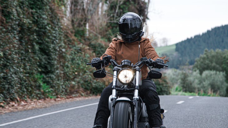 Mandy rides her motorcycle down a road with a full-face helmet on